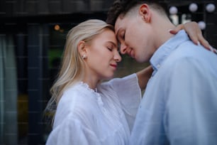 A young couple in love cuddling and kissing outdoors on terrace, weekend away in tiny house in countryside, sustainable living.