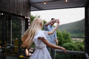 Una pareja joven bailando al aire libre, fin de semana en una pequeña casa en el campo, concepto de viaje y vacaciones.