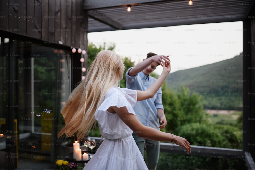A young couple dancing outdoors, weekend away in tiny house in countryside, travel and holiday concept.