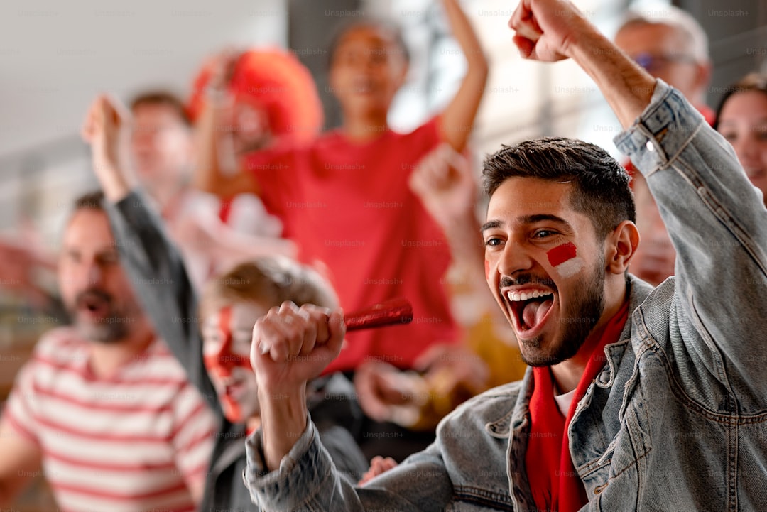 Excited football fans supproting an Austrian national team in live soccer match at stadium.