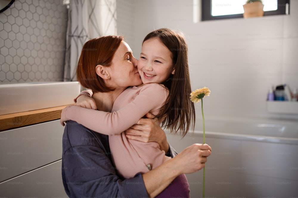 Una bambina si congratula con la mamma e dà il suo fiore nel bagno di casa.