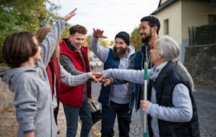 Un grupo diverso de voluntarios felices de servicio comunitario apilando manos juntas al aire libre en la calle