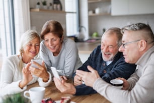 Um grupo de amigos idosos em casa, usando smartphones.
