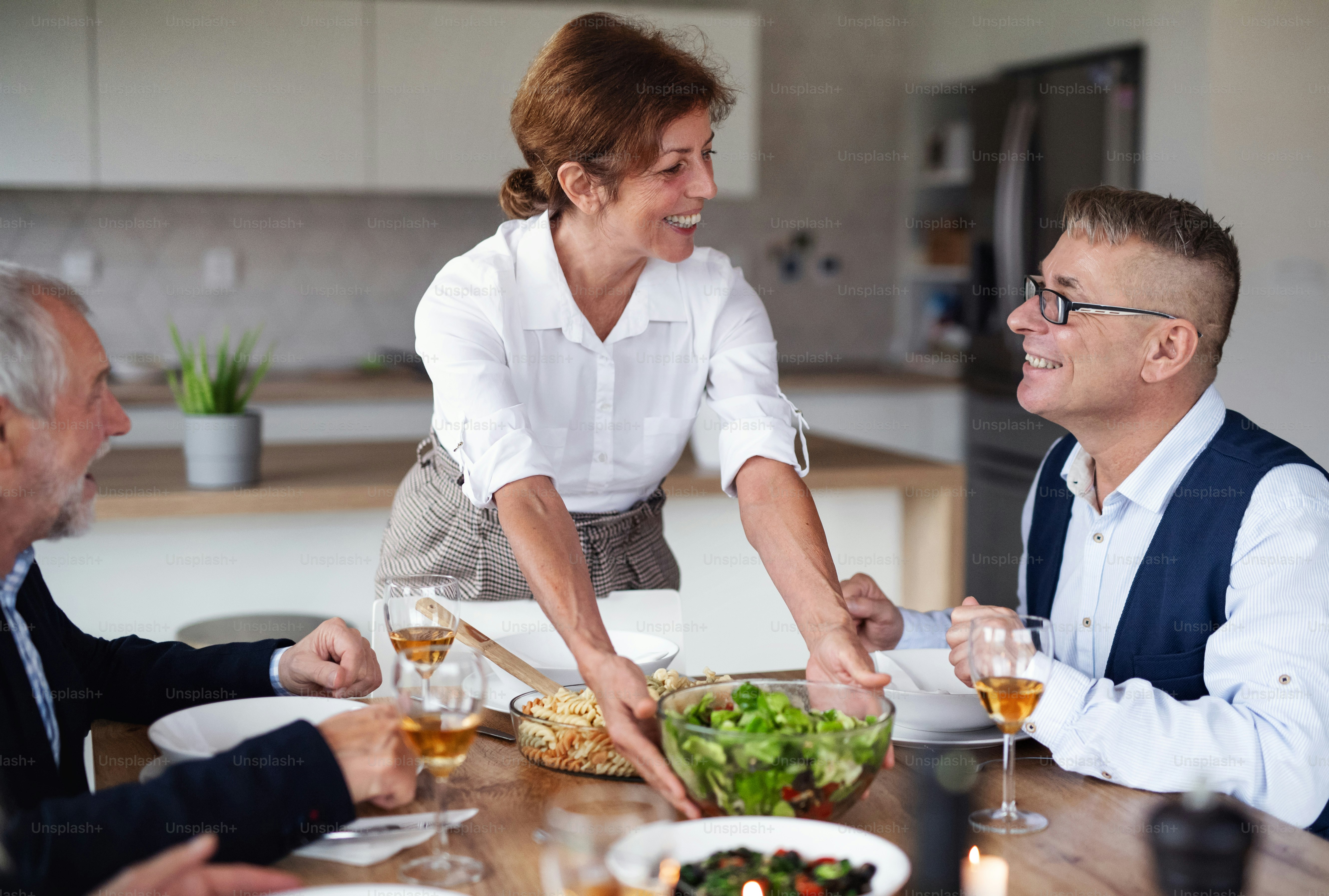 Gruppo di amici anziani che si godono la cena a casa.