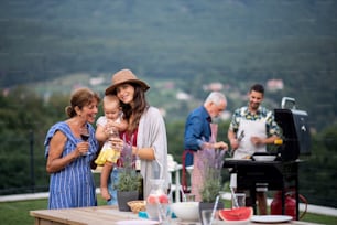 Mehrgenerationenfamilie mit Wein im Freien im Garten, Grillen, Grillen und Reden.