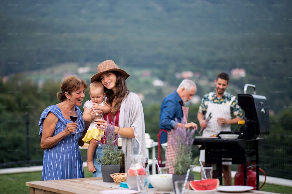 Familia multigeneracional con vino al aire libre en barbacoa de jardín, parrilla y charla.