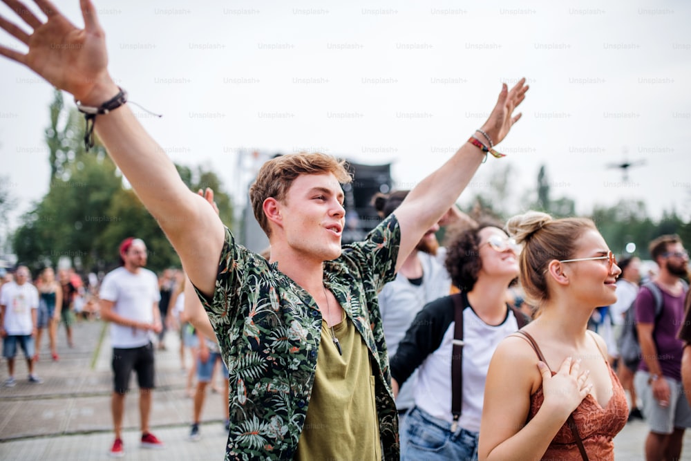 Grupo de jovens amigos alegres no festival de verão, dançando.