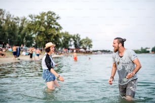 여름 축제에서 호수에 서서 즐거운 시간을 보내는 젊은 부부.