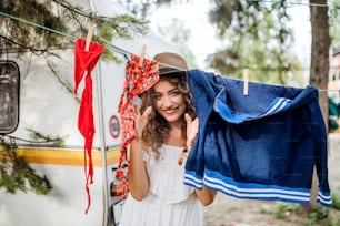 Mulher nova em férias de acampamento, pendurando roupas molhadas na linha de lavagem.