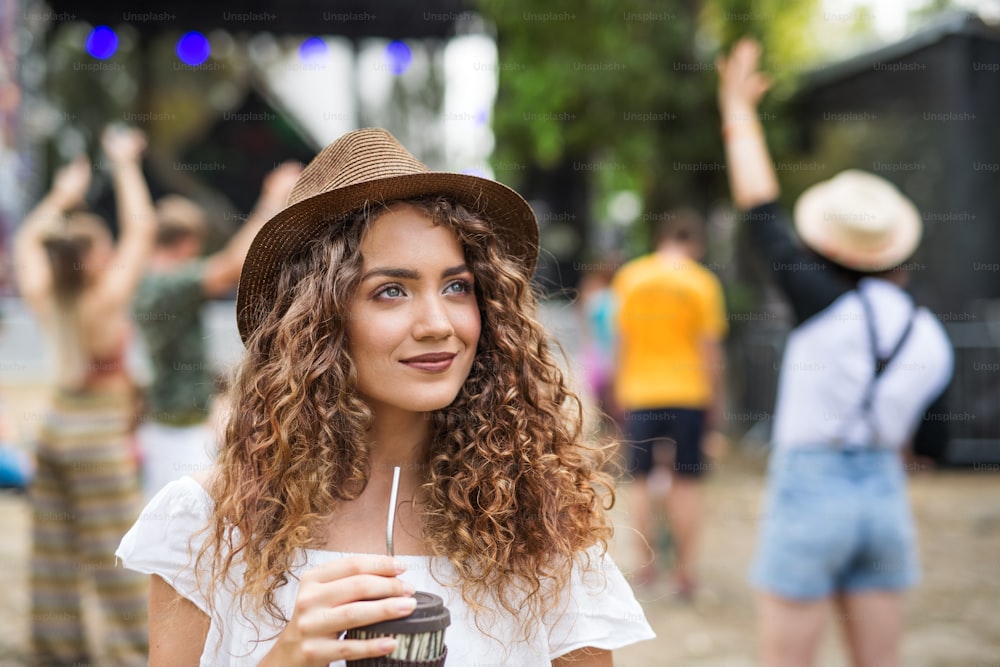Front view of a beautiful young girl at summer festival, holding drink.