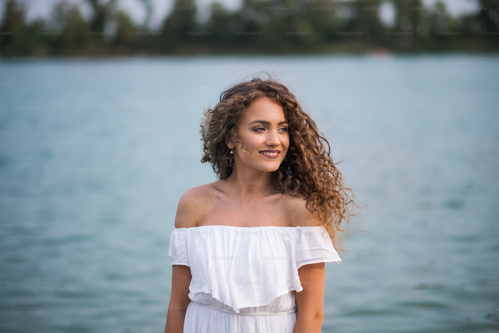 Front view of young woman at summer festival, standing in lake. Copy space.