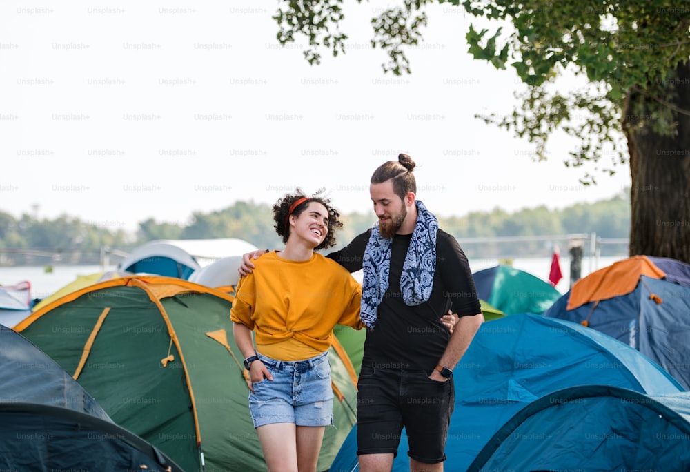 Jovem casal em férias de férias, andando de braços dados entre tendas.
