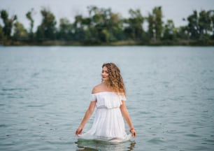Vista frontale della giovane donna al festival estivo, in piedi nel lago. Copia spazio.