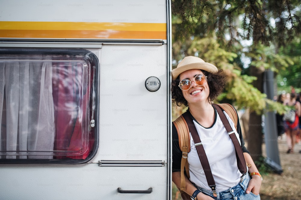 A portrait of young woman at summer festival, standing by caravan.