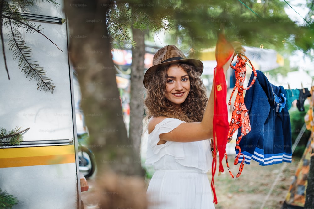 Front view of young woman hanging towels at summer festival or camping holiday.