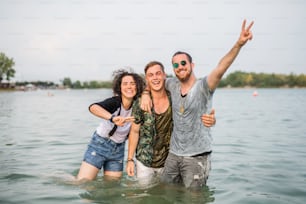 Gruppe junger Freunde beim Sommerfest, die im Wasser im See stehen.