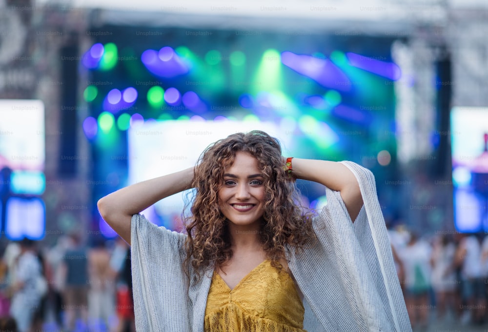 A beautiful young woman standing at summer festival, looking at camera.