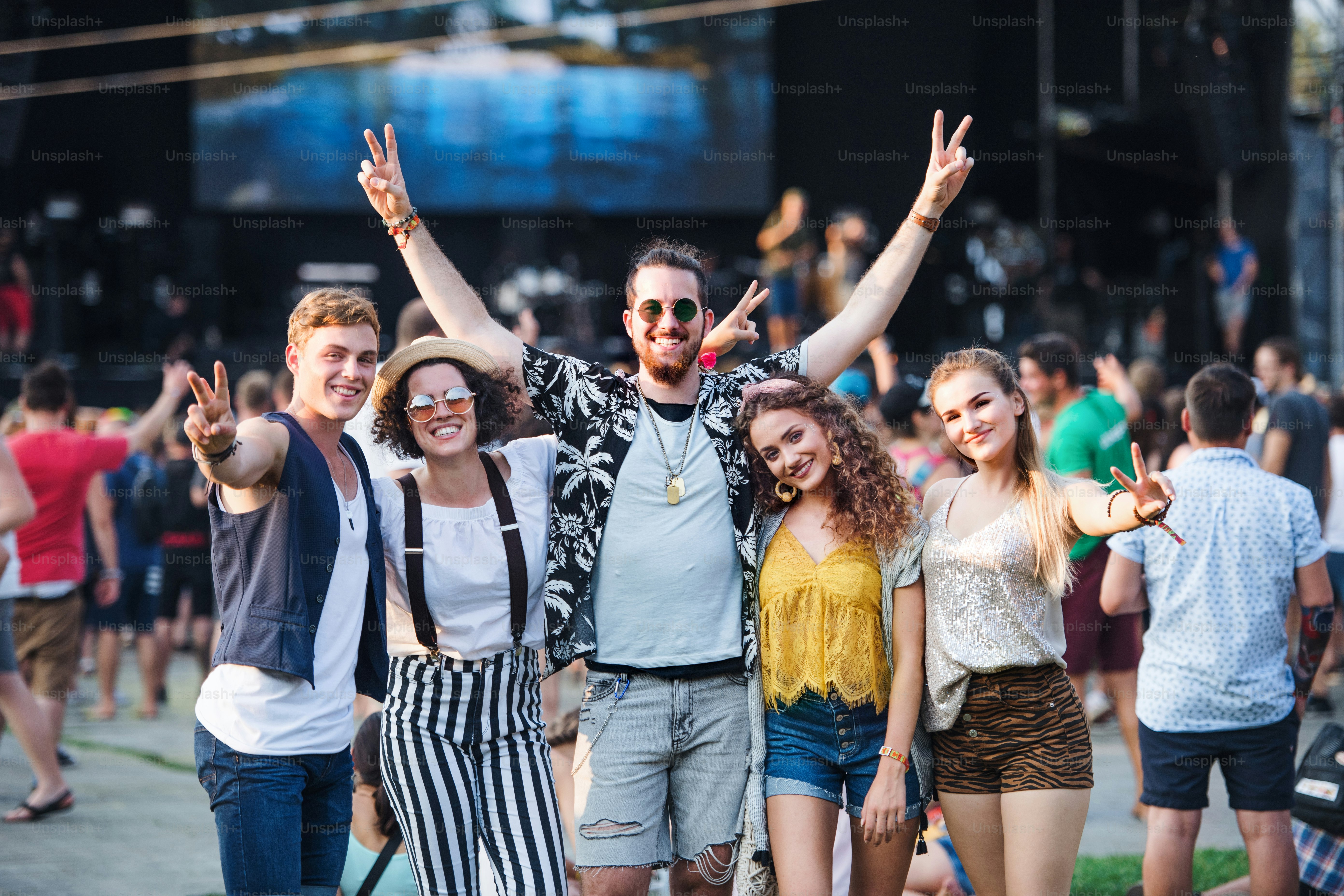 Group of cheerful young friends at summer festival, looking at camera.
