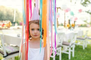 Small girl playing outdoors on garden party in summer, a celebration concept.