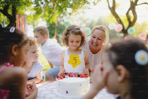 夏の庭で屋外の小さな女の子の誕生日パーティー、お祝いのコンセプト。
