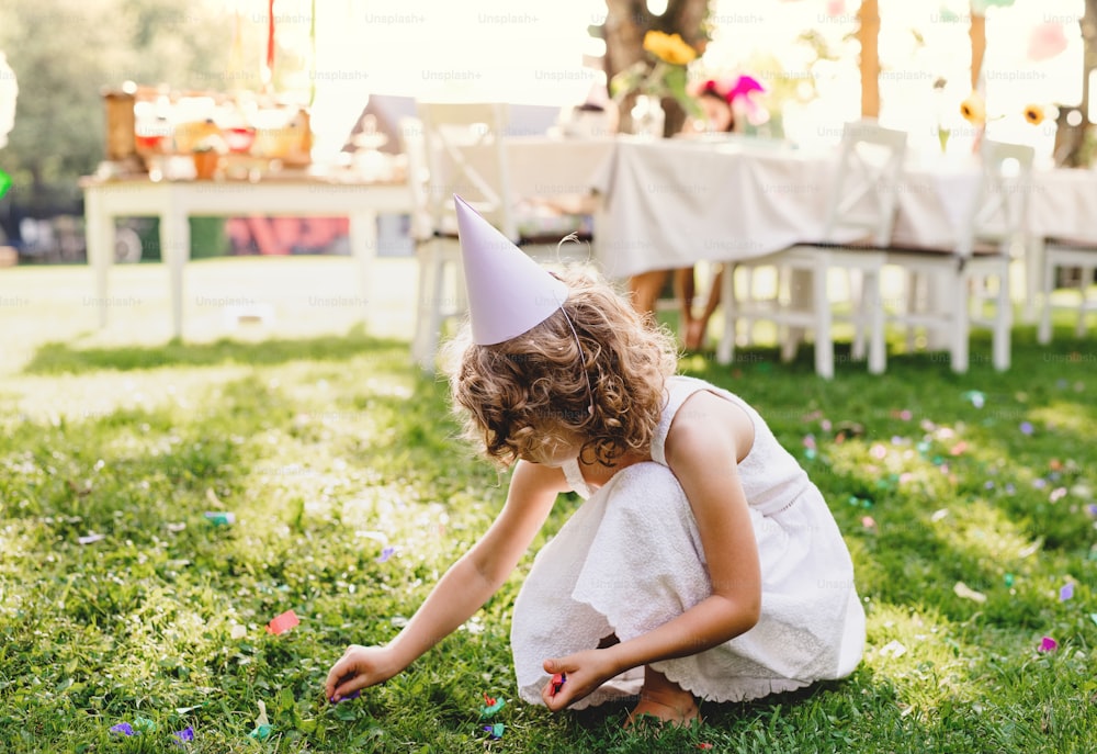 Kleines Mädchen, das im Sommer draußen auf einer Gartenparty spielt, ein Festkonzept.