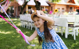 Menina pequena ao ar livre no jardim no verão, brincando com balões. Um conceito de celebração.