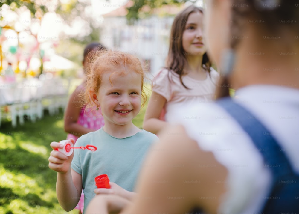 Bambini piccoli all'aperto in giardino in estate, giocando con le bolle. Un concetto di celebrazione.