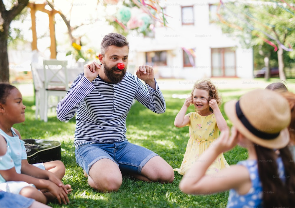어린 아이를 데리고 여름에 정원에서 야외에 앉아 놀고 있는 남자.