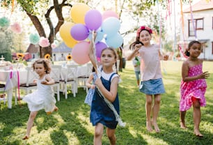 Bambini piccoli all'aperto in giardino in estate, giocando con i palloncini. Un concetto di celebrazione.