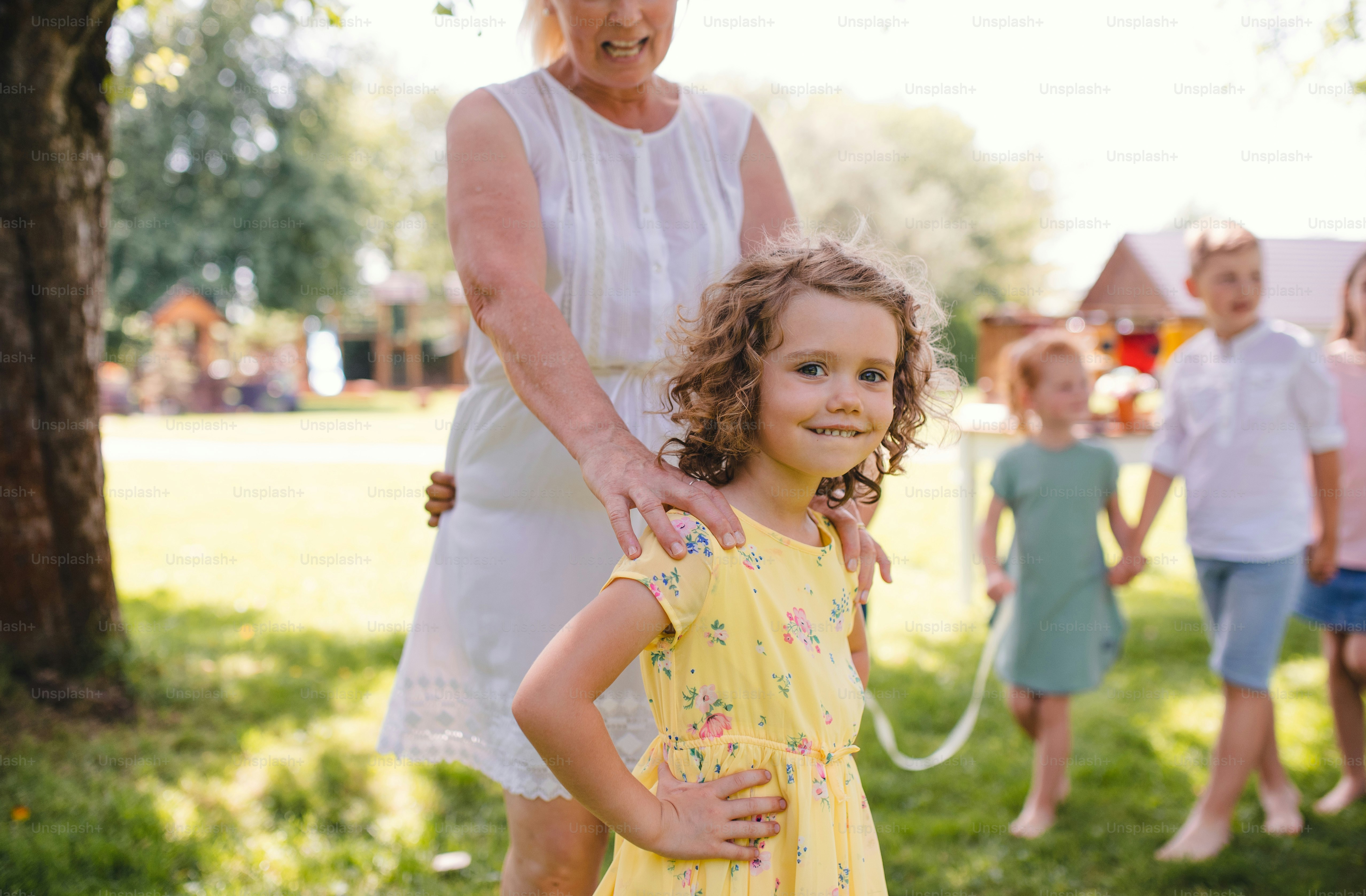 Petits enfants avec grand-mère dehors dans le jardin en été, jouant.