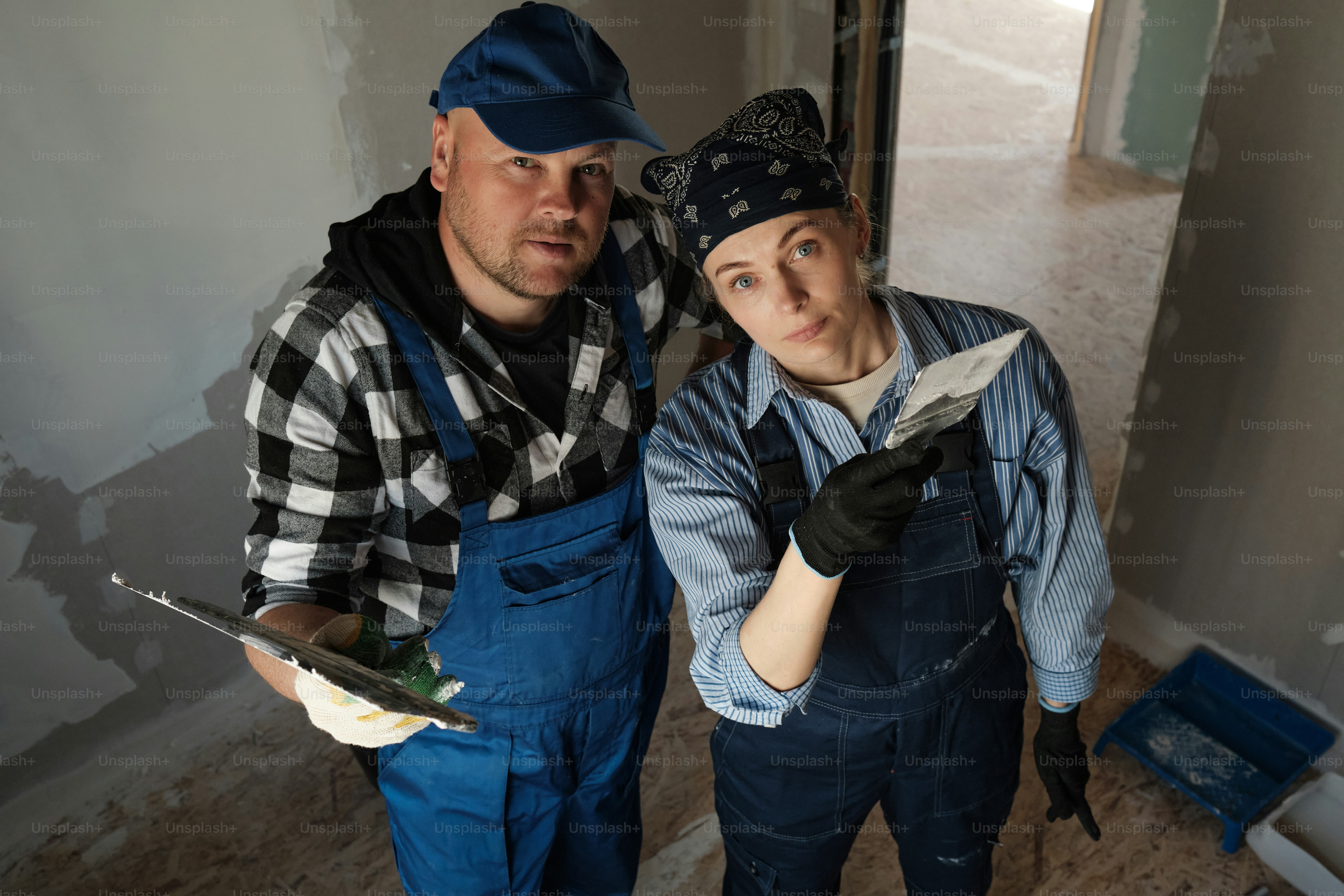 a couple looking into a camera in a house under construction