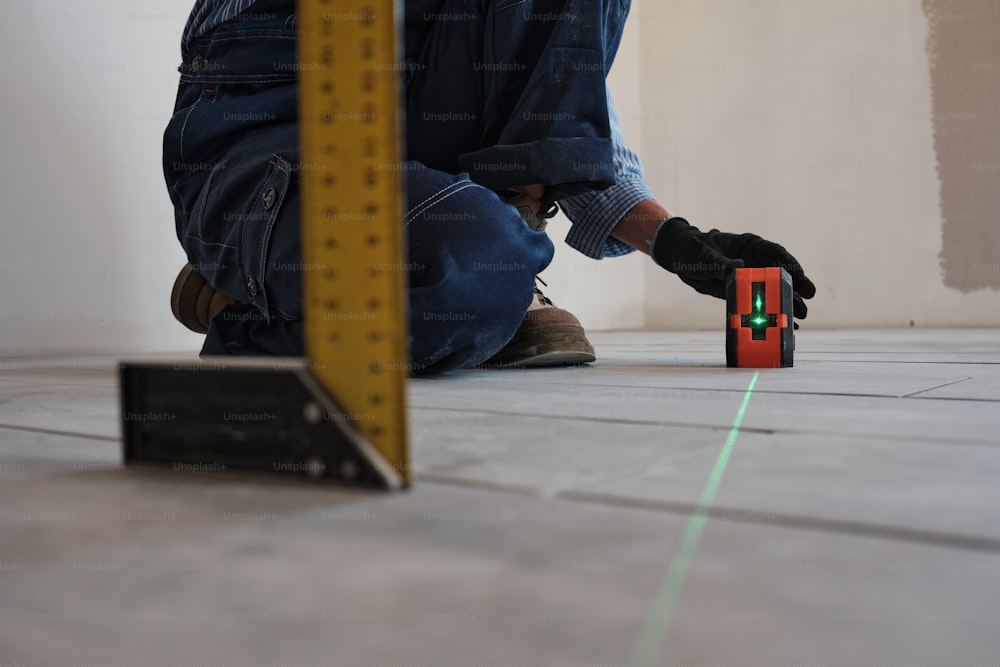 a man kneeling down on the floor with a tape measure