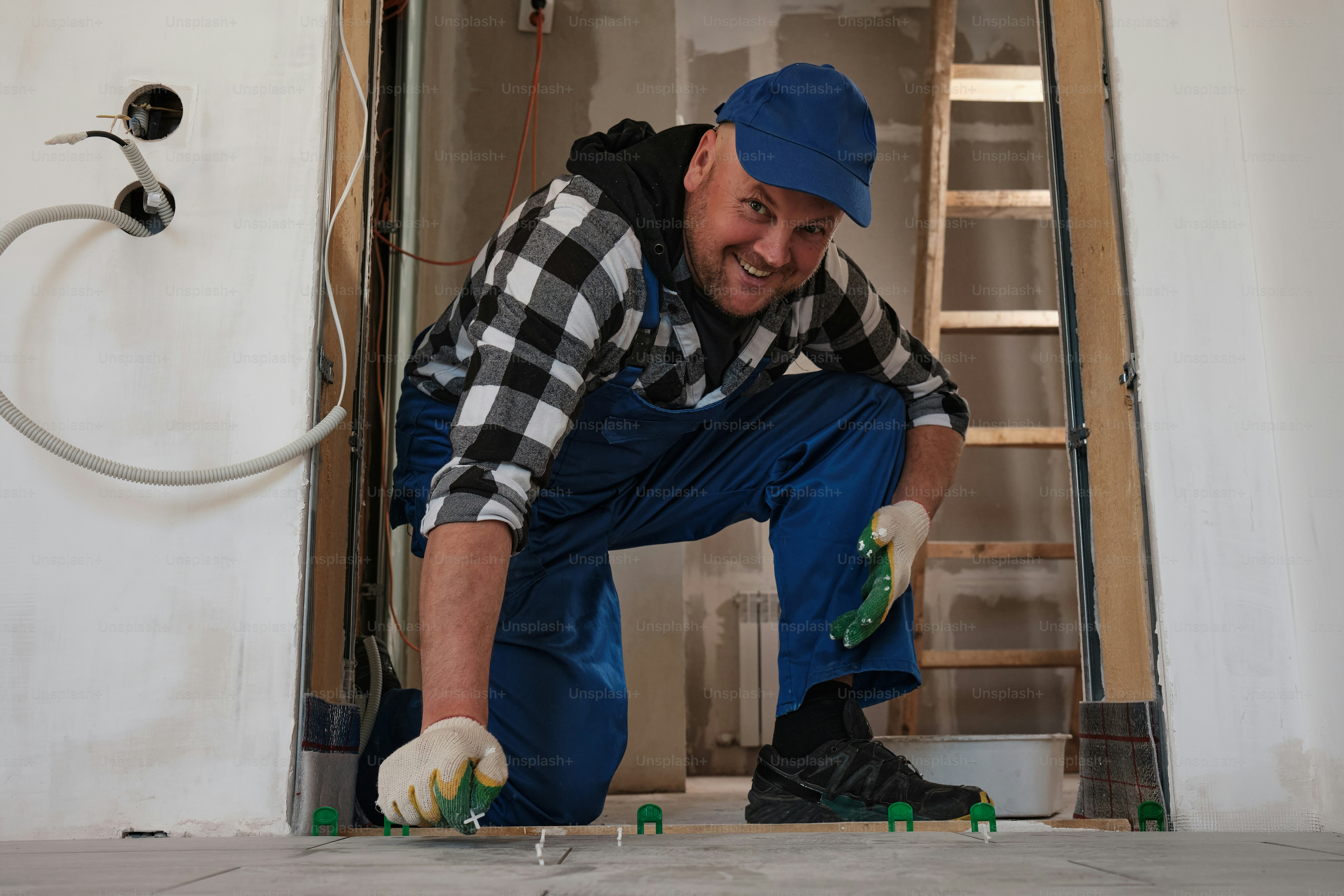 a man in overalls and a blue hat working on a floor