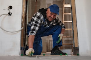 a man in overalls and a blue hat working on a floor