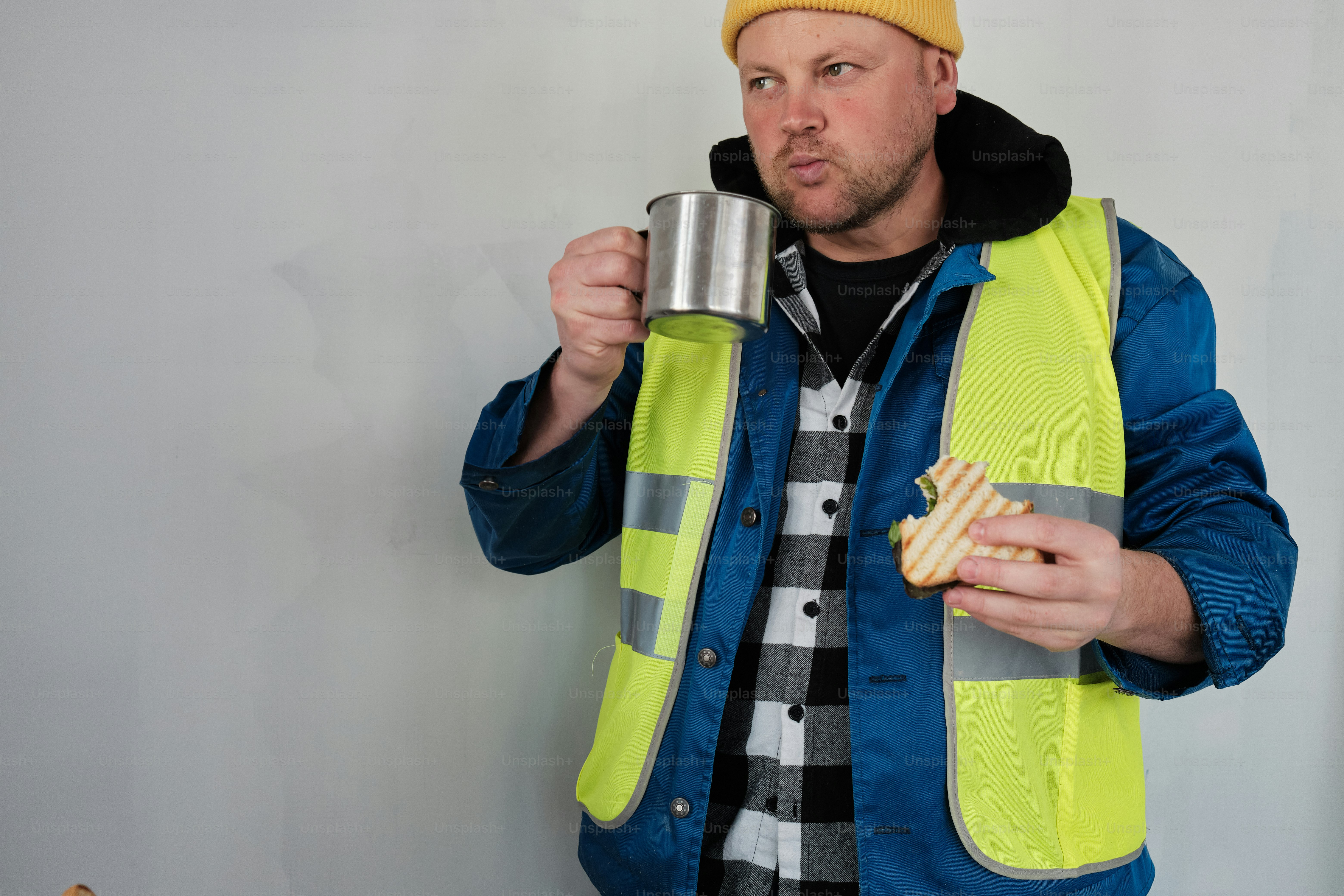 Ein Mann mit gelbem Hut, der eine Tasse und einen Donut hält