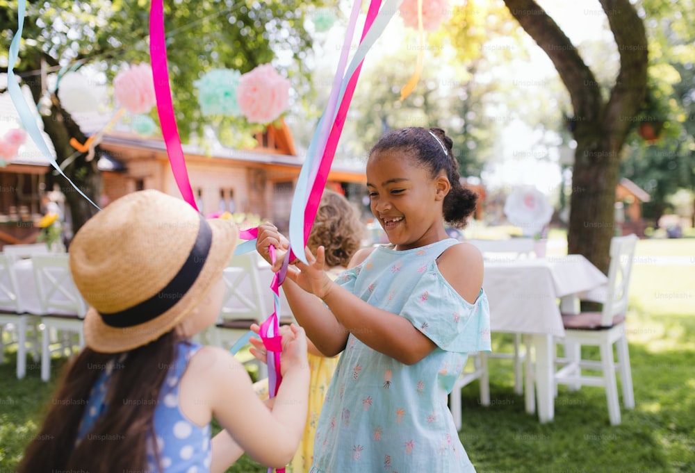 Small children outdoors in garden in summer, playing. A celebration concept.