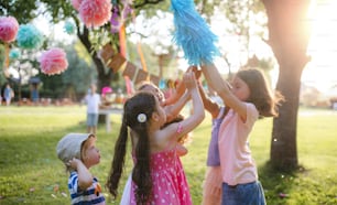Small children with kite outdoors in garden in summer, playing. A celebration concept.