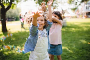 Small children standing outdoors in garden in summer, playing. A celebration concept.