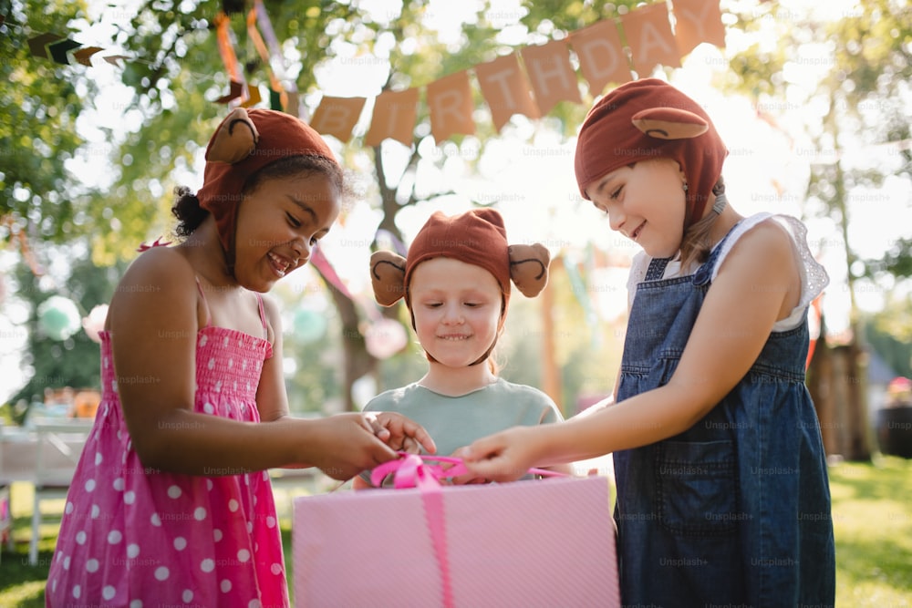 Petits enfants avec des masques et présents dans une boîte debout à l’extérieur dans le jardin en été.