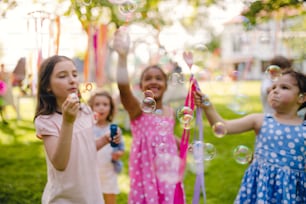 Niños pequeños parados al aire libre en el jardín en verano, jugando. Un concepto de celebración.