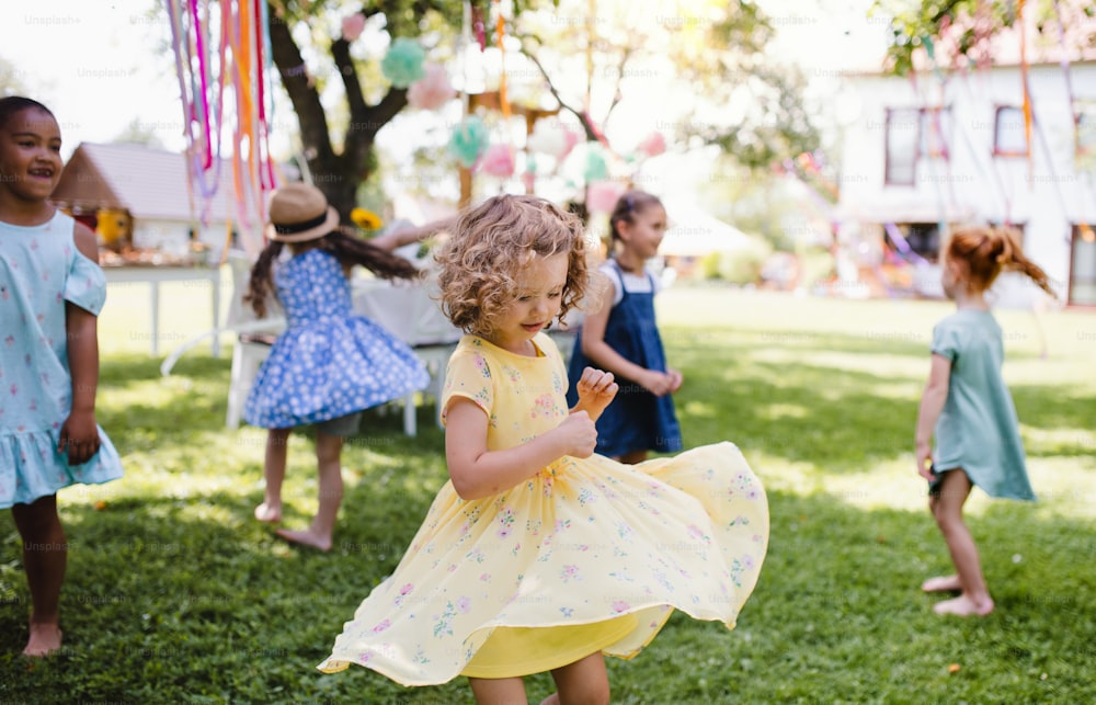 Bambini piccoli in piedi all'aperto in giardino in estate, giocando. Un concetto di celebrazione.