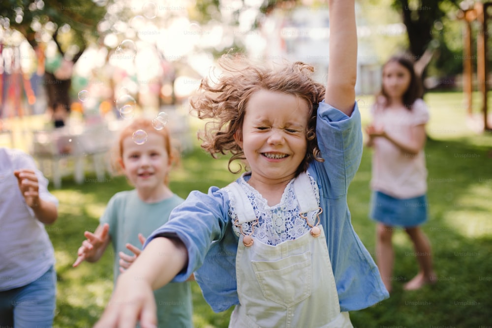 Crianças pequenas em pé ao ar livre no jardim no verão, brincando. Um conceito de celebração.
