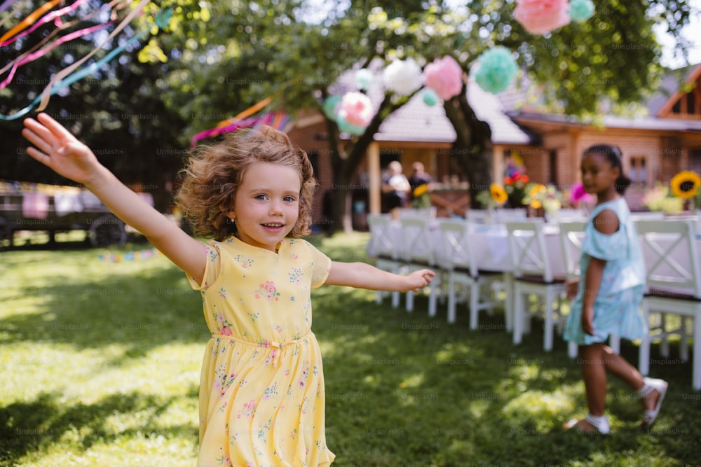 Bambina che corre all'aperto in giardino in estate, un concetto di festa di compleanno.