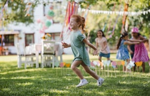 Small children running outdoors in garden in summer, playing. A celebration concept.