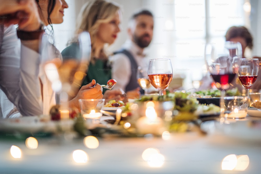 Una grande famiglia felice seduta a un tavolo in una festa di compleanno al coperto, mangiando.