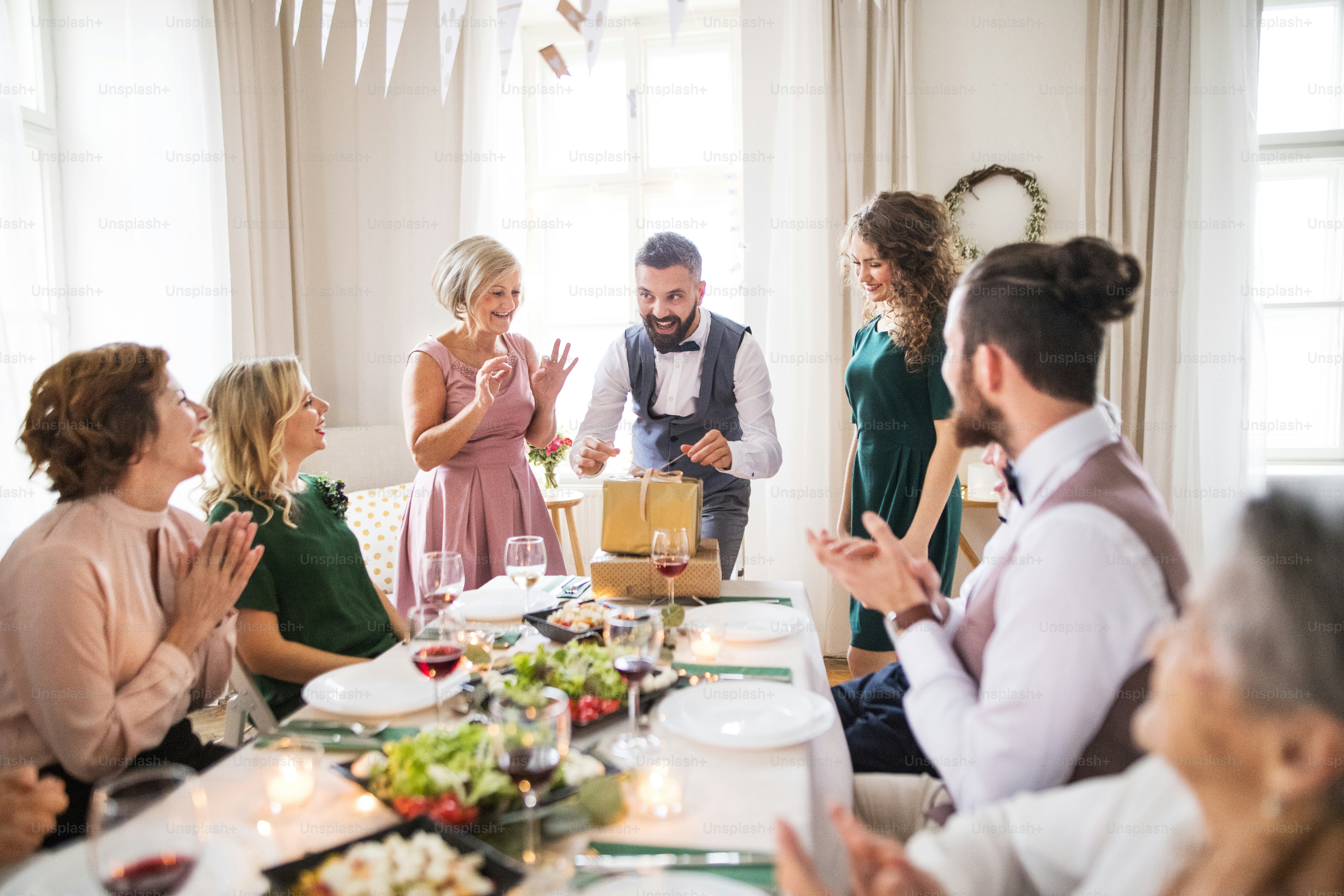 Un uomo maturo felice con amici e familiari che aprono i regali per una festa di compleanno.