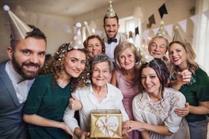 Um retrato de uma família de várias gerações com presentes em pé dentro de uma festa de aniversário.