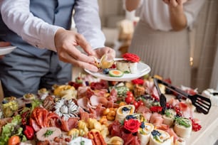 Sección media de un hombre poniendo comida en un plato en una fiesta de cumpleaños familiar en el interior.