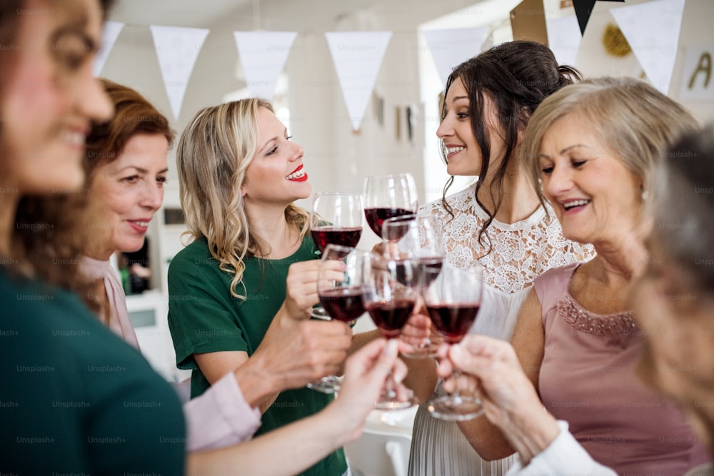 A multigeneration family clinking glasses with red wine on a indoor family birthday party, making a toast.