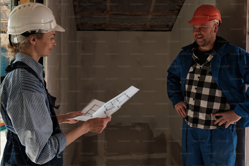 a man and a woman in hardhats looking at a blueprint